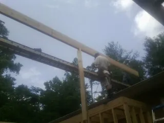 Carpenter setting a ridge beam over a new addition frame — Ice Dam Removal by Roofing Brothers in Conesus