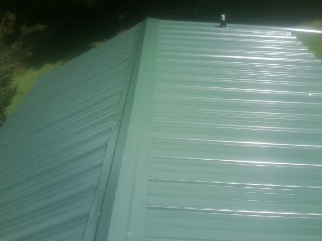 New green metal panels meeting at the ridge of a roof — Flat Roof Repair work by our crew in Conesus