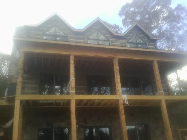 Dormers and porch framing on a large log home under construction — Roof Coating work by our crew in Conesus