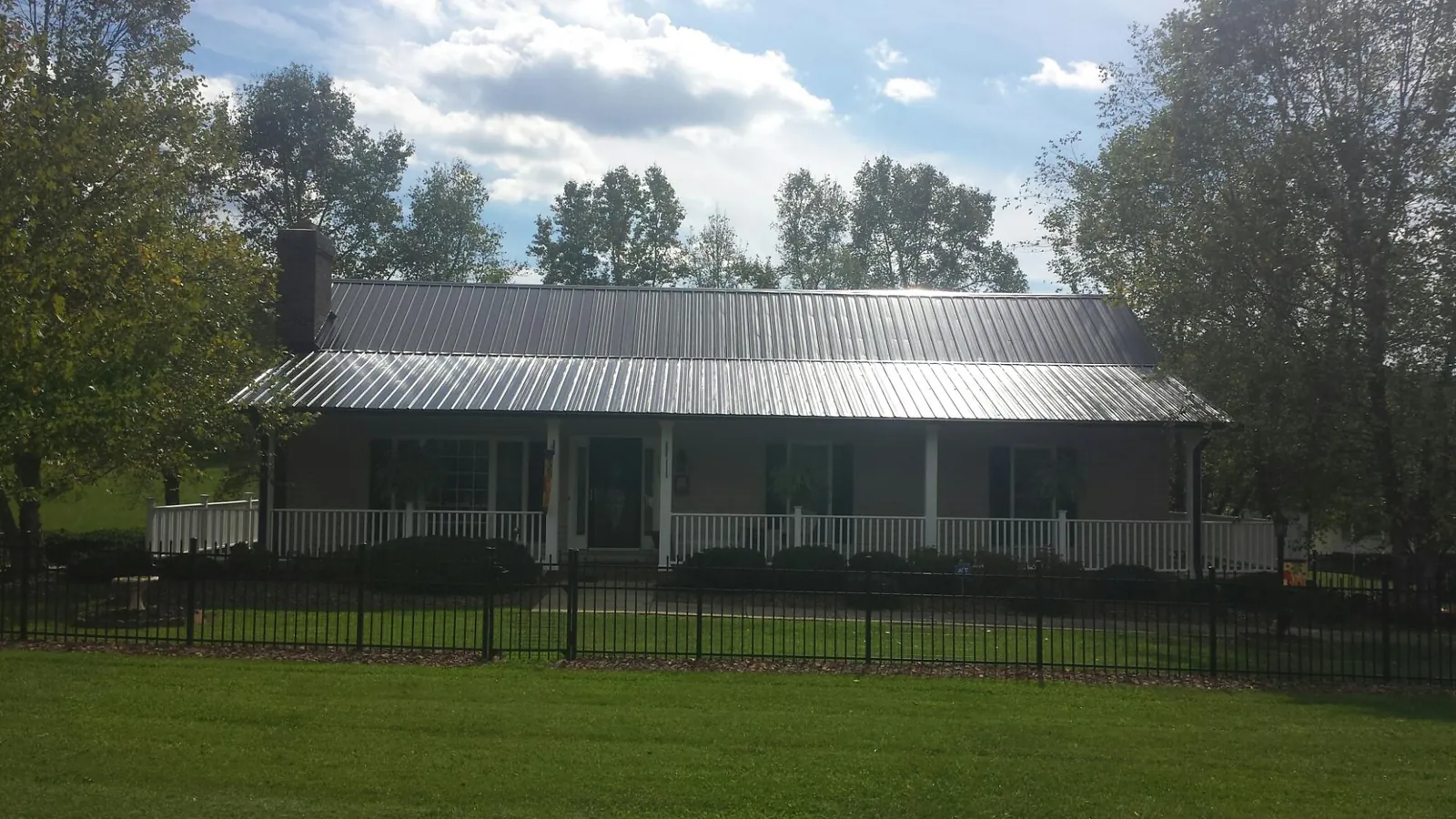 Gray metal roof on a brick ranch with a full width front porch — Gutter Guard Installation work by our crew in Conesus