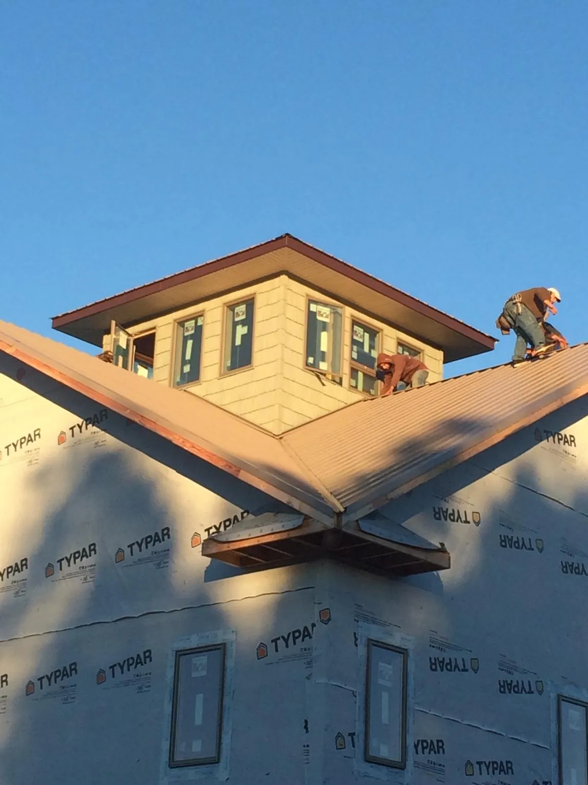 Roofers working around a rooftop cupola on a new metal roof at sunset — Roof Waterproofing in Conesus by Roofing Brothers